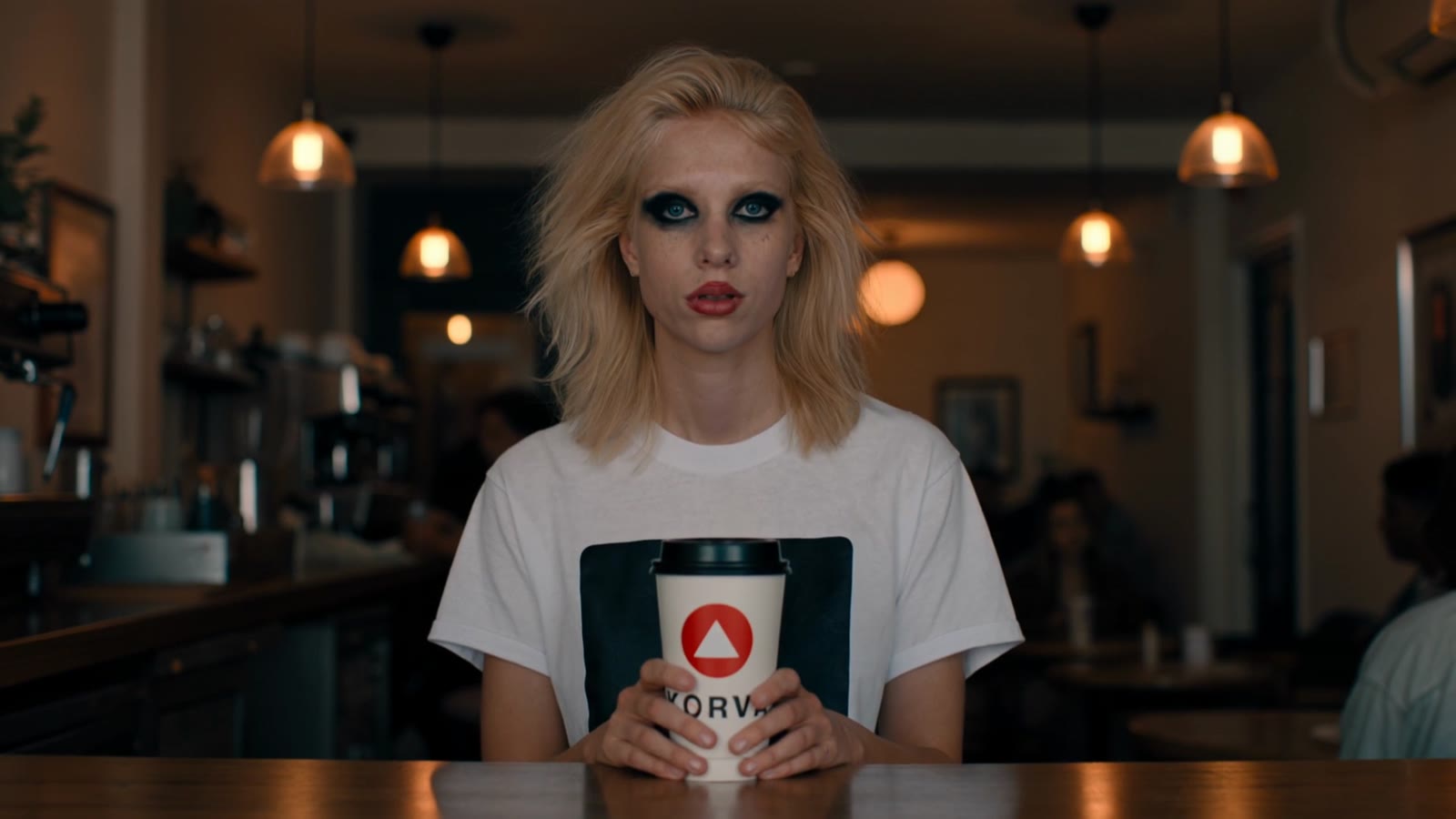 Mid-clip frame: Lilly holding the cup, the KORVA mark facing camera, partly behind her fingers.